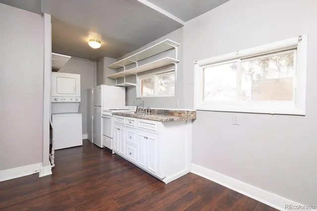a kitchen with granite countertop white cabinets and wooden floor