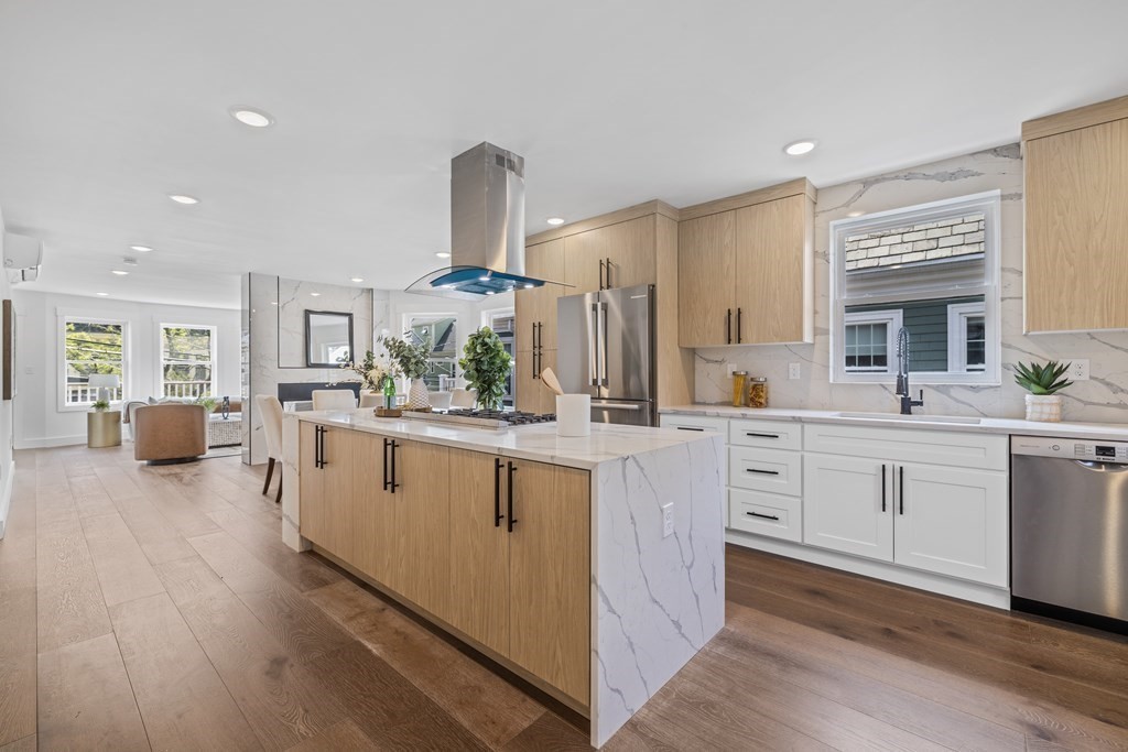 a large white kitchen with stainless steel appliances a lot of counter space and wooden floors