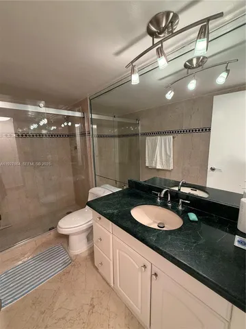 a bathroom with a granite countertop sink a toilet a mirror and shower
