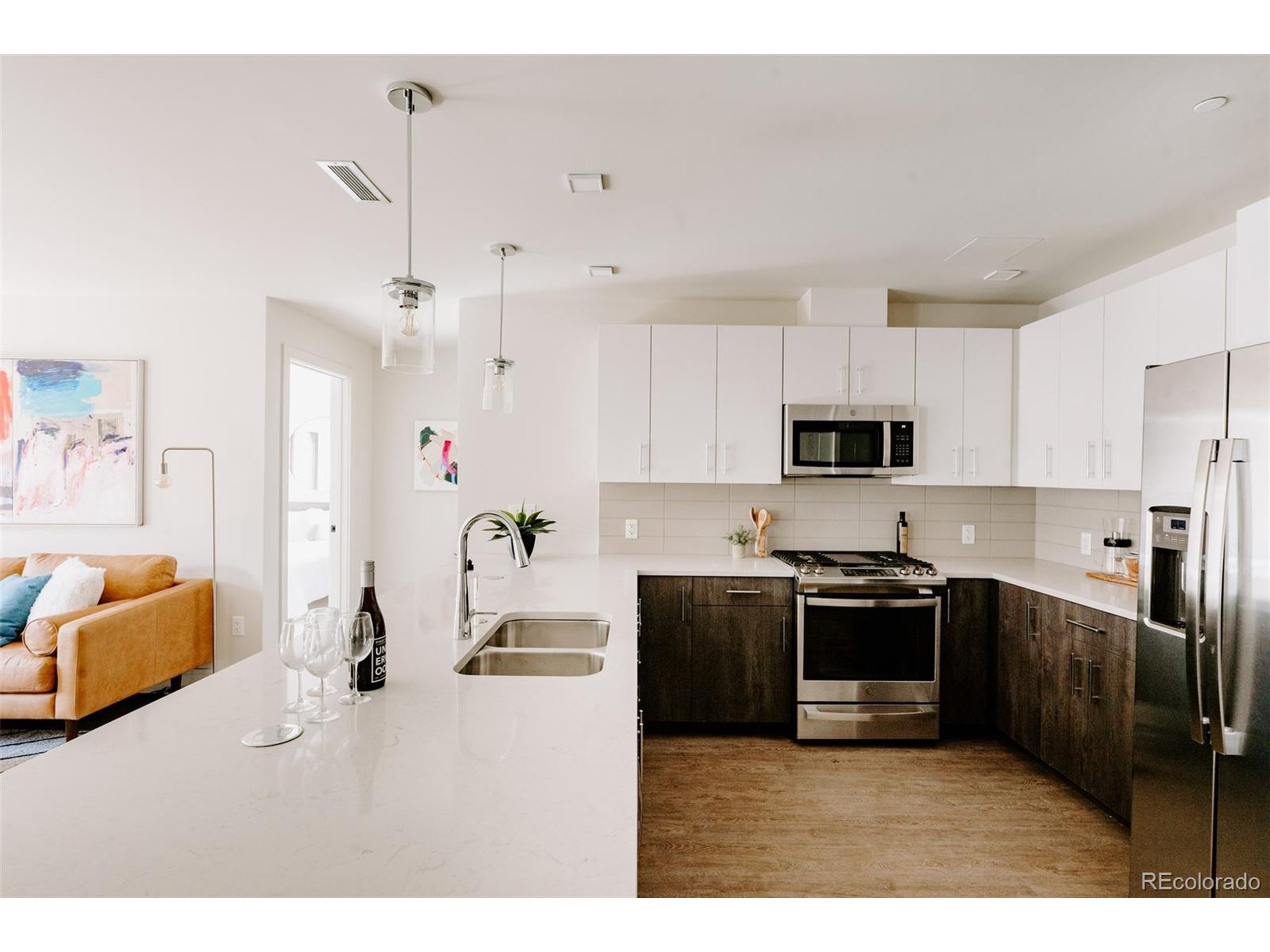 a kitchen with stainless steel appliances granite countertop a stove top oven a sink dishwasher a refrigerator and white cabinets with wooden floor