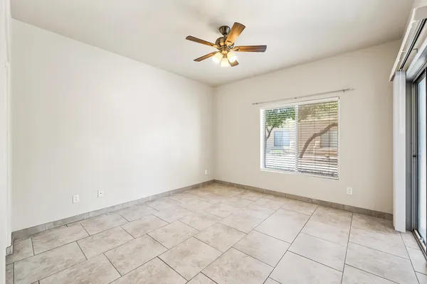 an empty room with chandelier fan and windows