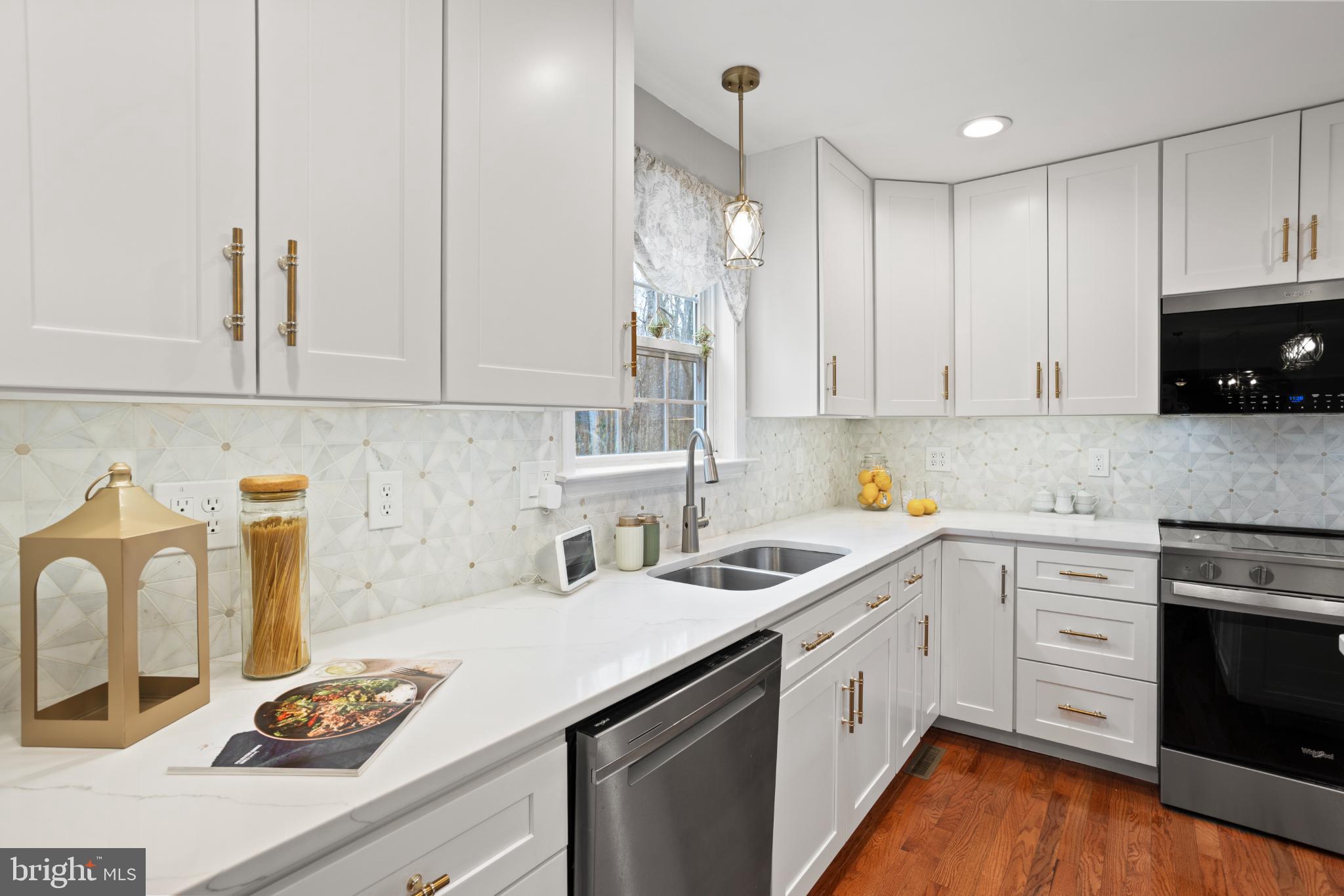 1860 Battery Lane Owings, MD 20736 - Photo 21 of 120 a kitchen with stainless steel appliances granite countertop a sink stove and white cabinets with wooden floor