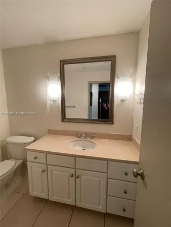a bathroom with a granite countertop sink mirror and toilet