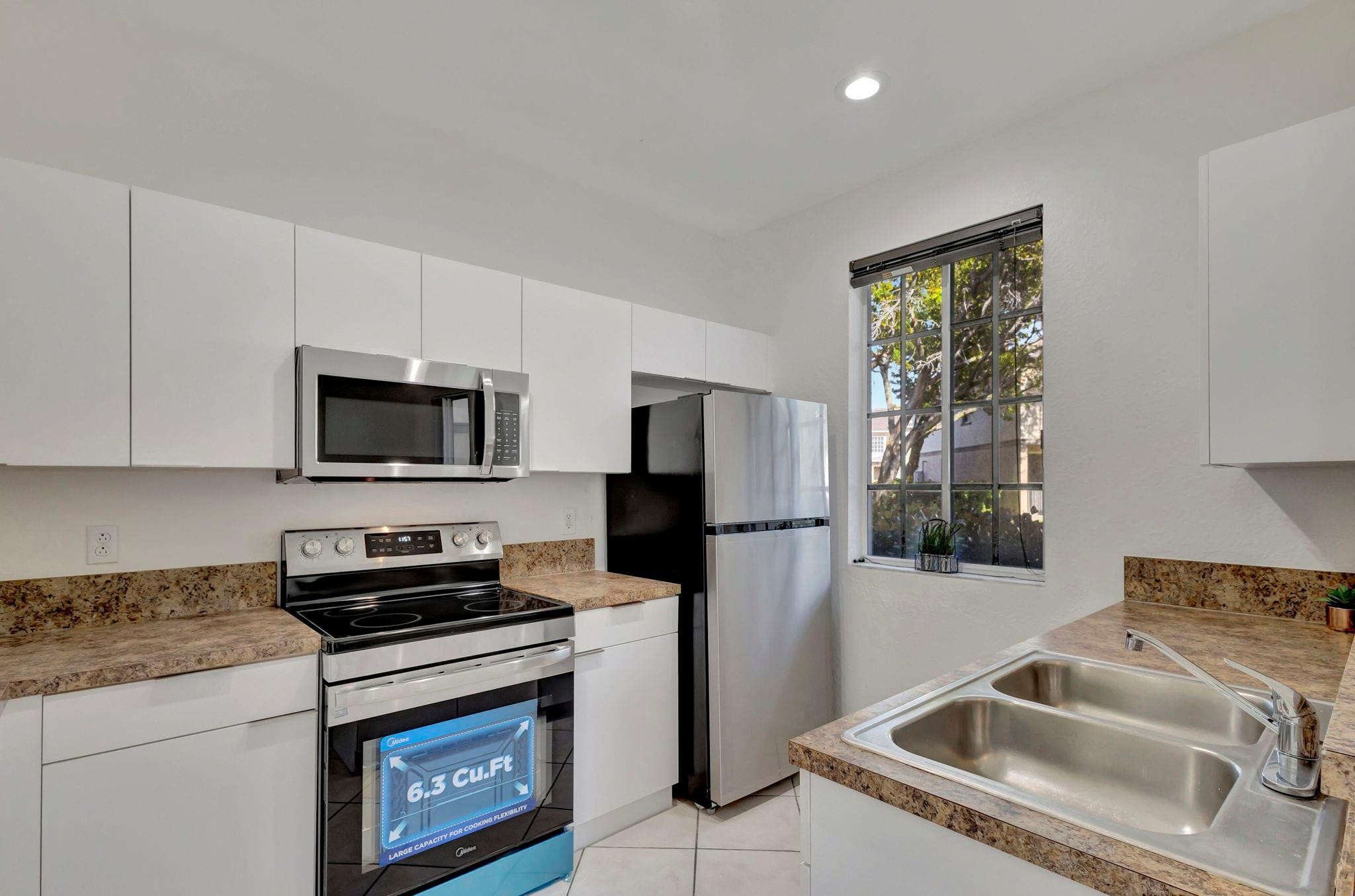 1000 Flamingo Place Riviera Beach, FL 33404 - Photo 28 of 83 a kitchen with stainless steel appliances granite countertop a refrigerator a stove a microwave oven with white cabinets and wooden floor