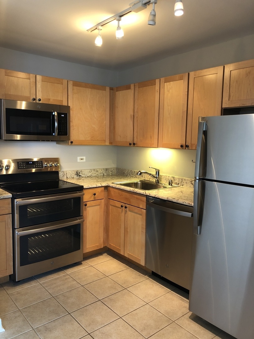 655 West Irving Park Road, Unit 3804 Chicago, IL 60613 - Photo 2 of 8 a kitchen with granite countertop a refrigerator and a stove top oven