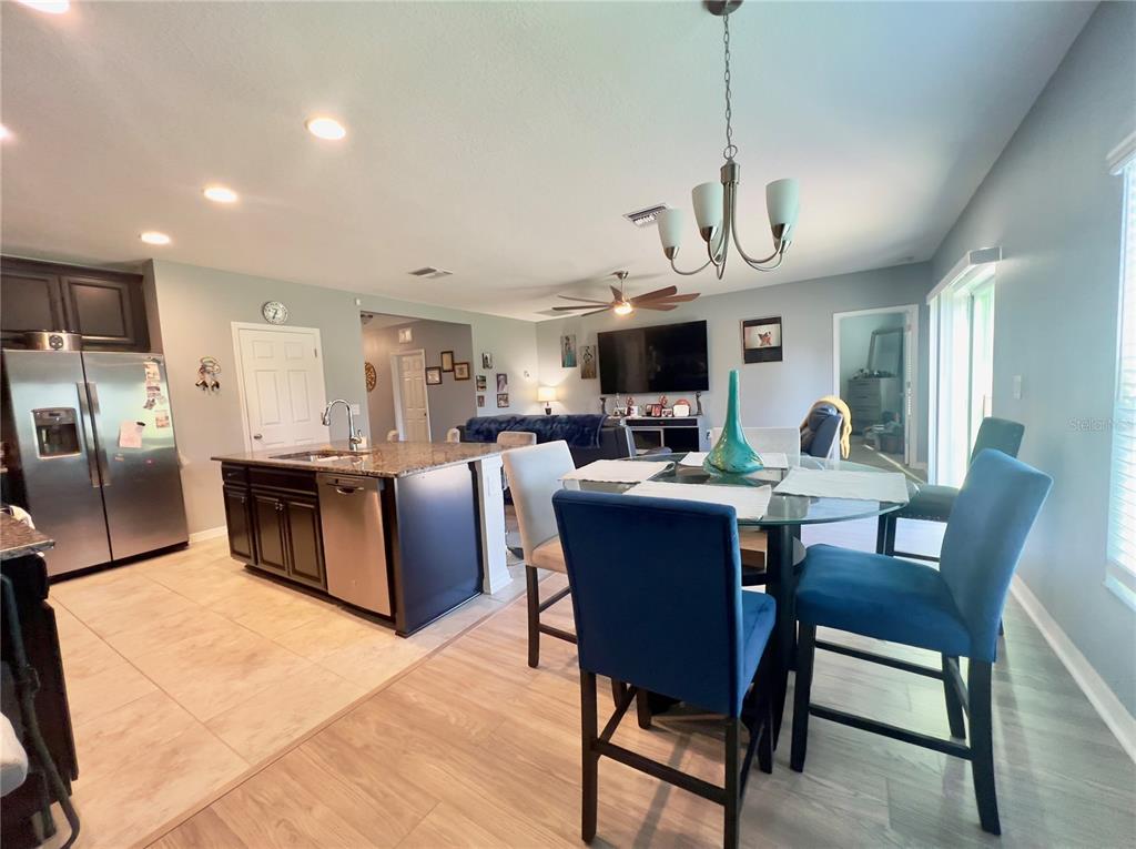 13149 Conquistador Loop Spring Hill, FL 34610 - Photo 15 of 30 a living room with stainless steel appliances kitchen island granite countertop a dining table chairs and a refrigerator