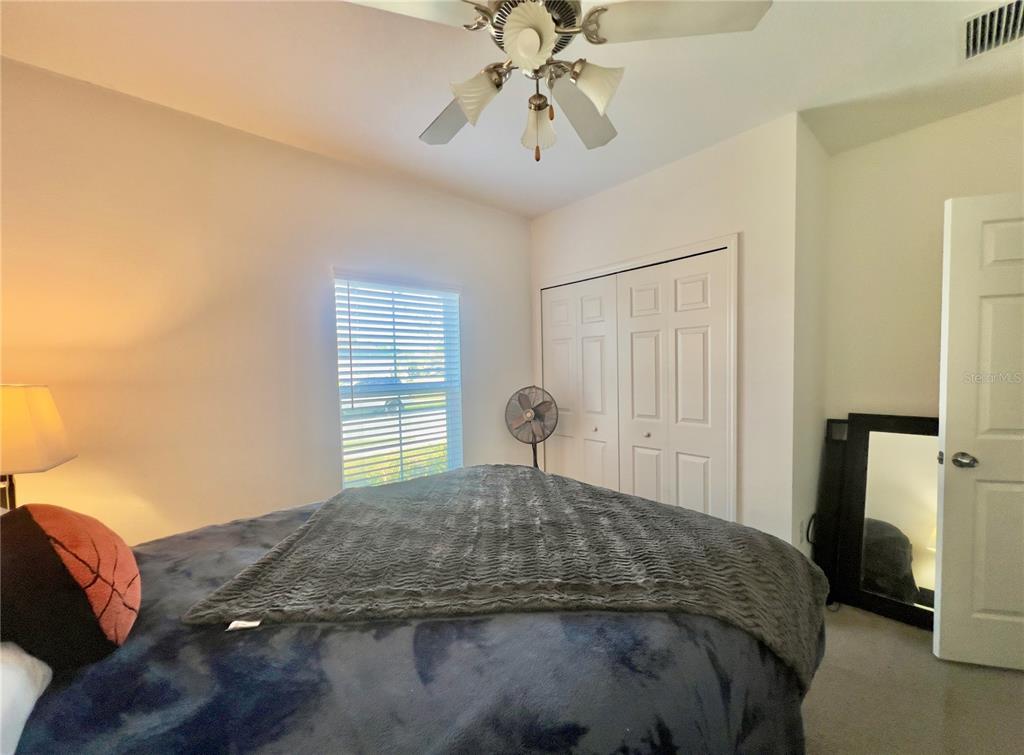 13149 Conquistador Loop Spring Hill, FL 34610 - Photo 23 of 30 a bedroom with a bed and a chandelier
