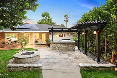 a view of a backyard with table and chairs potted plants and large tree