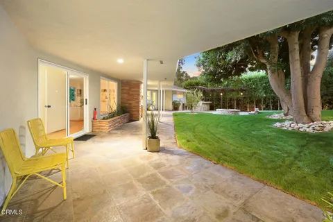 a view of a patio with table and chairs potted plants and floor to ceiling window