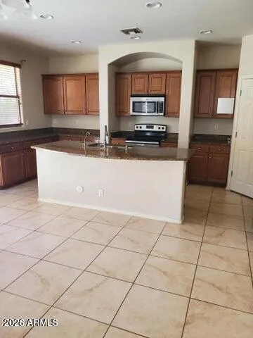 a large kitchen with granite countertop a stove a sink a counter space and cabinets