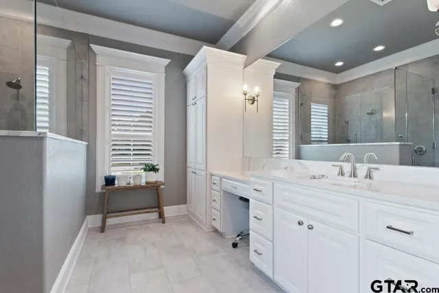 a spacious bathroom with a double vanity sink a mirror a bathtub and window