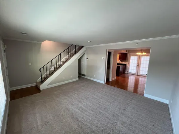a view of an empty room with wooden floor and stairs