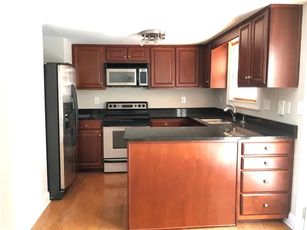 a kitchen with stainless steel appliances granite countertop a stove a sink and a microwave