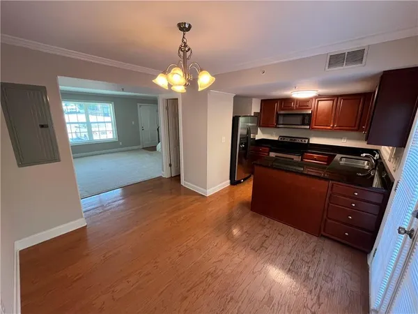 a kitchen with stainless steel appliances granite countertop a refrigerator a sink dishwasher a stove and a dining table with wooden floor