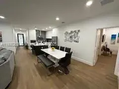 a living room with furniture and a dining table with wooden floor