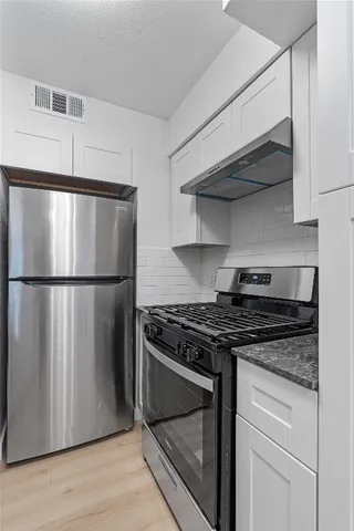 a kitchen with stainless steel appliances granite countertop a stove a refrigerator and a microwave