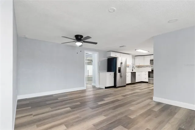 a view of empty room with wooden floor and fan