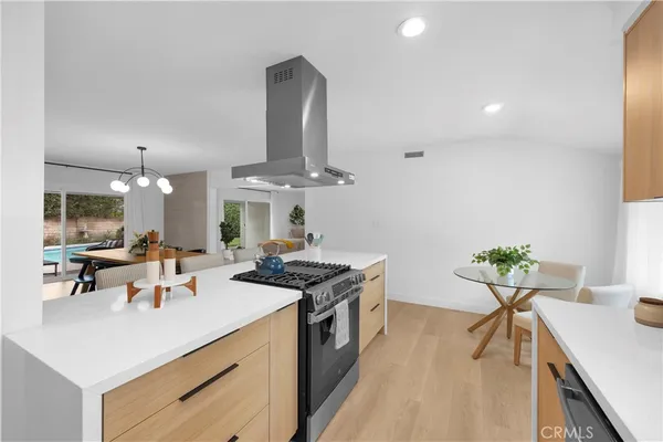 a kitchen with stainless steel appliances a sink a stove and chairs