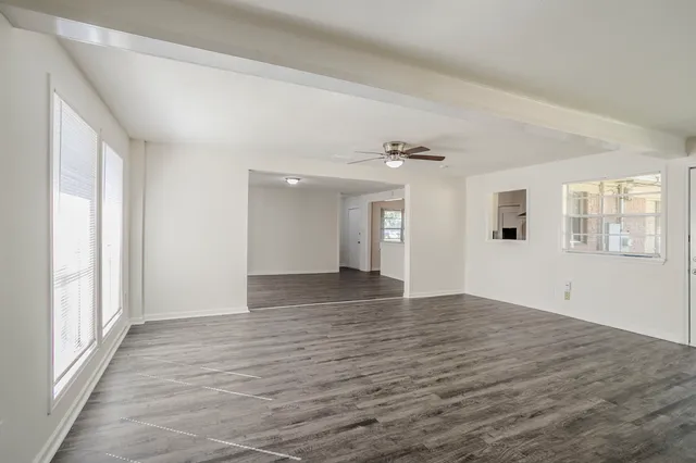 a view of an empty room with window and wooden floor