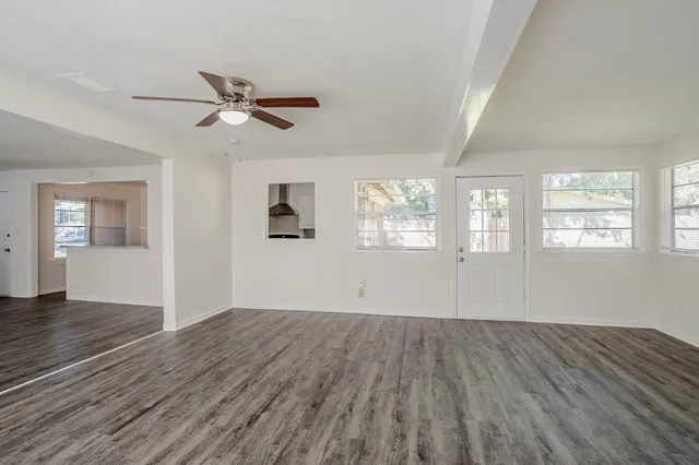 a view of empty room with wooden floor and fan