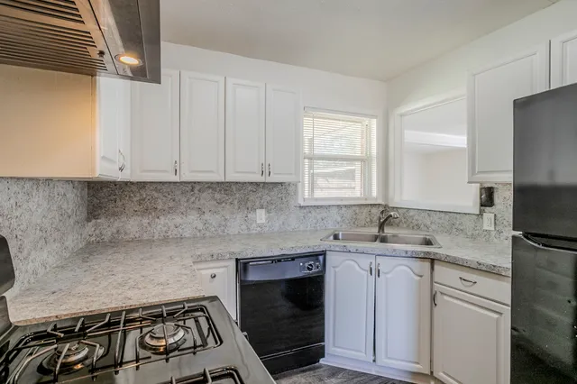 a kitchen with granite countertop a sink stove and cabinets