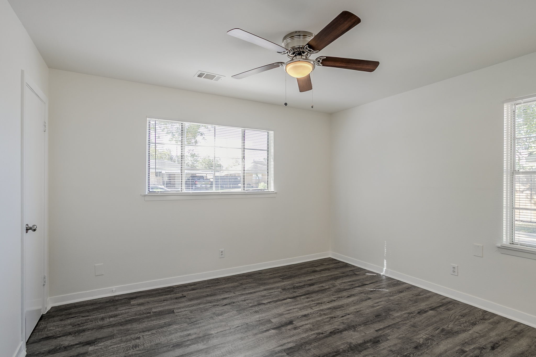 6434 Leader Street Houston, TX 77074 - Photo 10 of 46 an empty room with wooden floor chandelier fan and windows