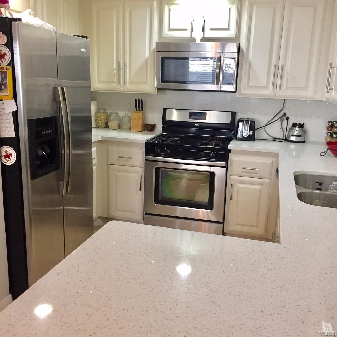 532 Spring Road, Unit 102 Moorpark, CA 93021 - Photo 3 of 10 a kitchen with stainless steel appliances a stove a microwave and a refrigerator