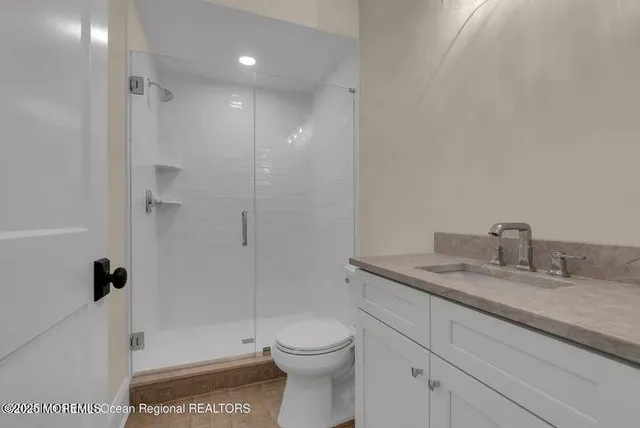 a bathroom with a granite countertop sink a toilet and shower