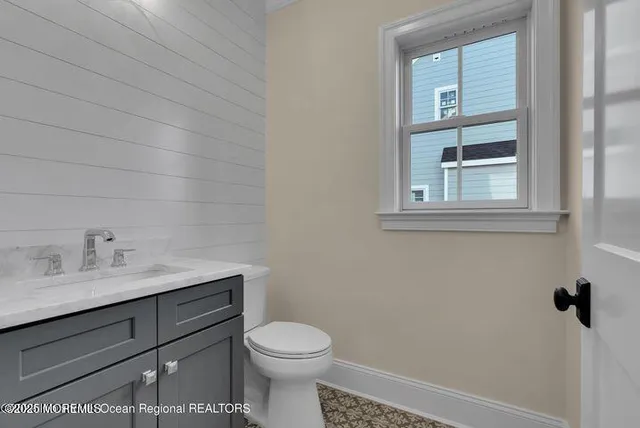 a bathroom with a toilet sink vanity and window