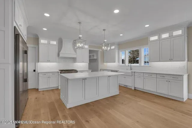 a large kitchen with kitchen island white cabinets and stainless steel appliances