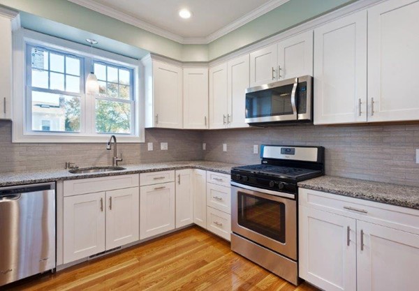 49 Tarbox Street Dedham, MA 02026 - Photo 11 of 30 a kitchen with stainless steel appliances granite countertop a sink a stove and microwave with wooden floor