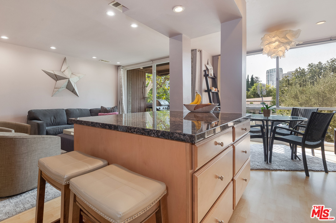 a living room with stainless steel appliances kitchen island granite countertop furniture and a wooden floor