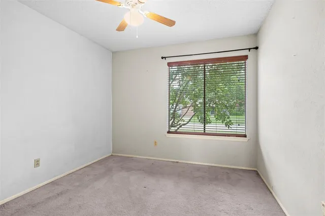 an empty room with windows and chandelier fan