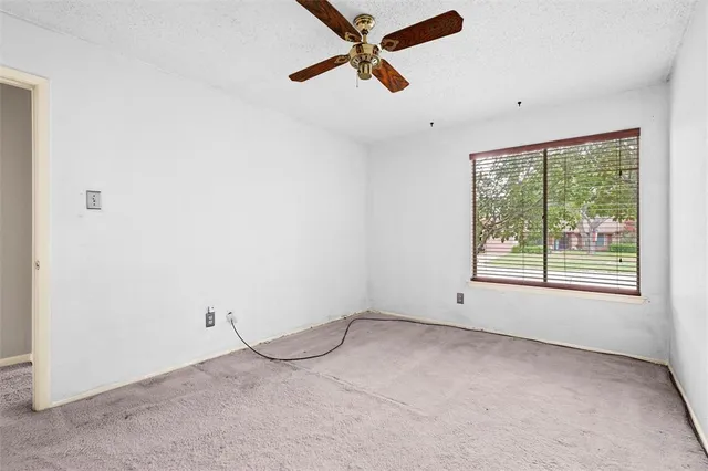 an empty room with a window and a ceiling fan