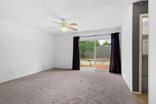 an empty room with floor to ceiling windows and a ceiling fan