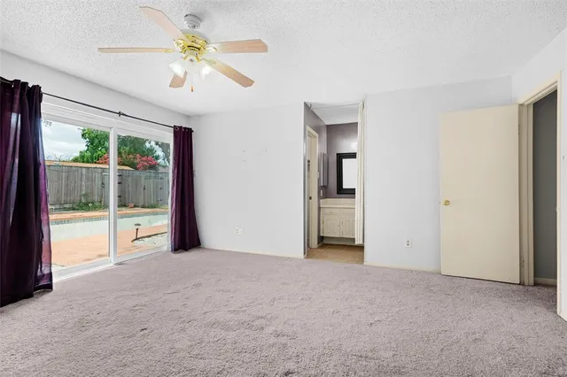an empty room with chandelier fan and windows