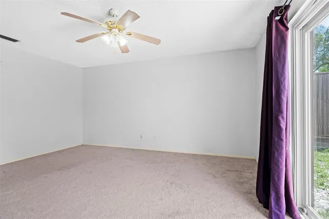 an empty room with windows and fan