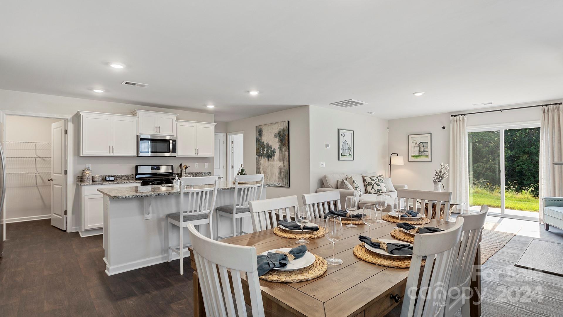 509 Jaca Lane Arden, NC 28704 - Photo 7 of 28 a living room with stainless steel appliances kitchen island granite countertop a dining table chairs and a refrigerator