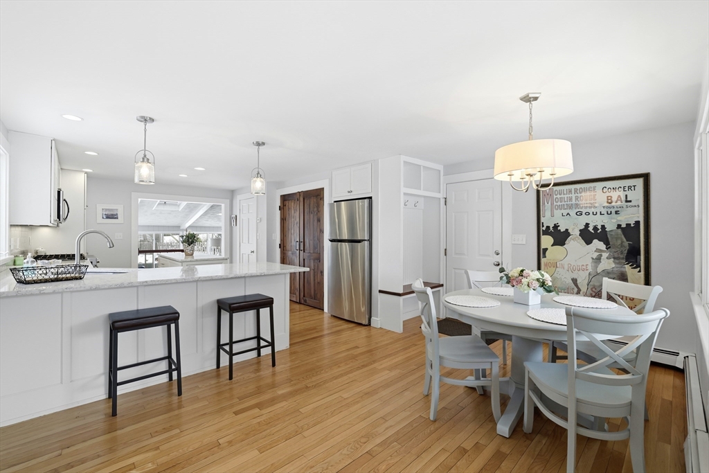 63 Bancroft Road Cohasset, MA 02025 - Photo 5 of 41 a dining room with wooden floor a chandelier a wooden table and chairs