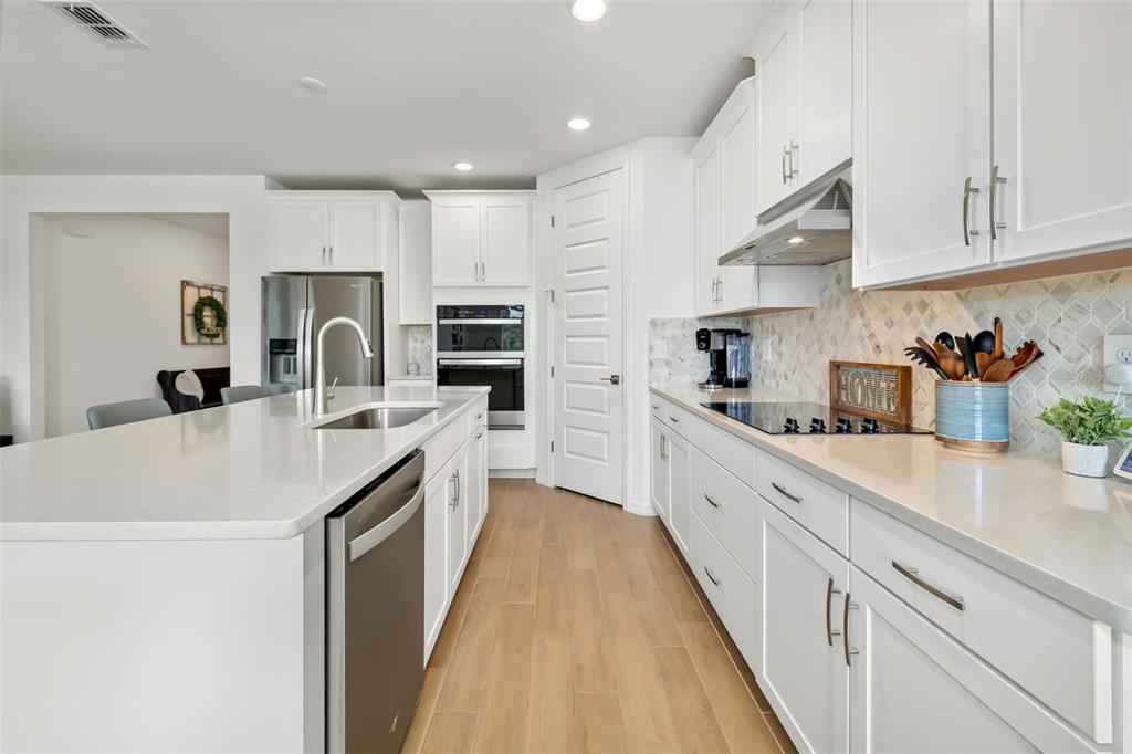14086 Ginnie Spgs Way Parrish, FL 34219 - Photo 26 of 49 a large kitchen with kitchen island a sink a counter space and stainless steel appliances