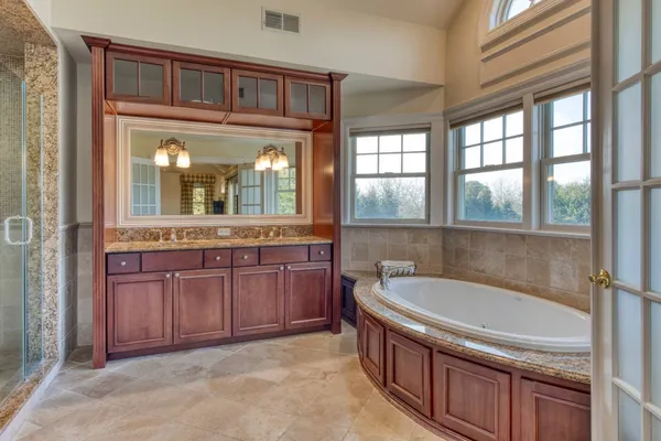 a bathroom with a granite countertop tub sink and mirror