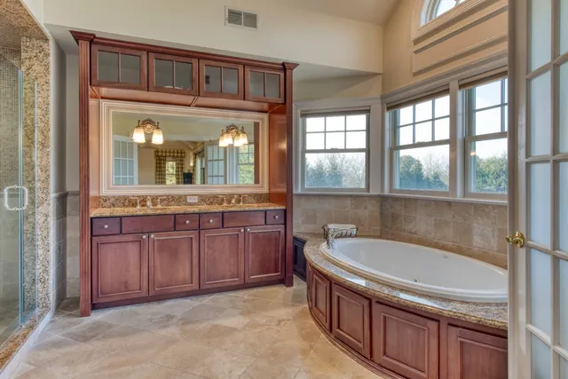 a bathroom with a granite countertop tub sink and mirror