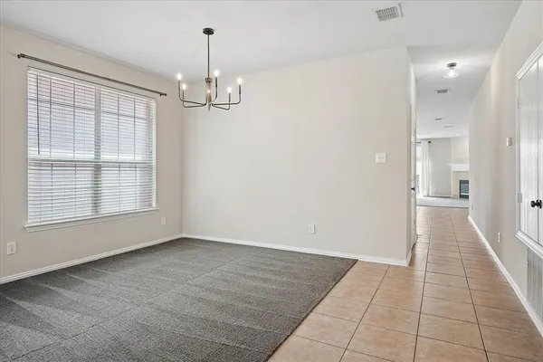 an empty room with kitchen view and a chandelier
