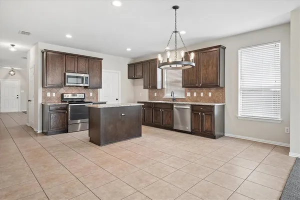 a kitchen with stainless steel appliances granite countertop a stove top oven a sink and a refrigerator