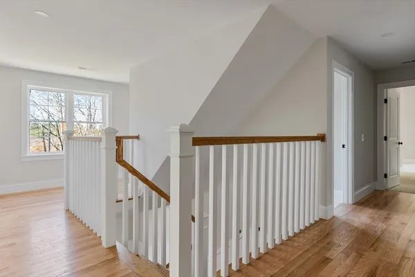 a view of a hallway with wooden floor and stairs