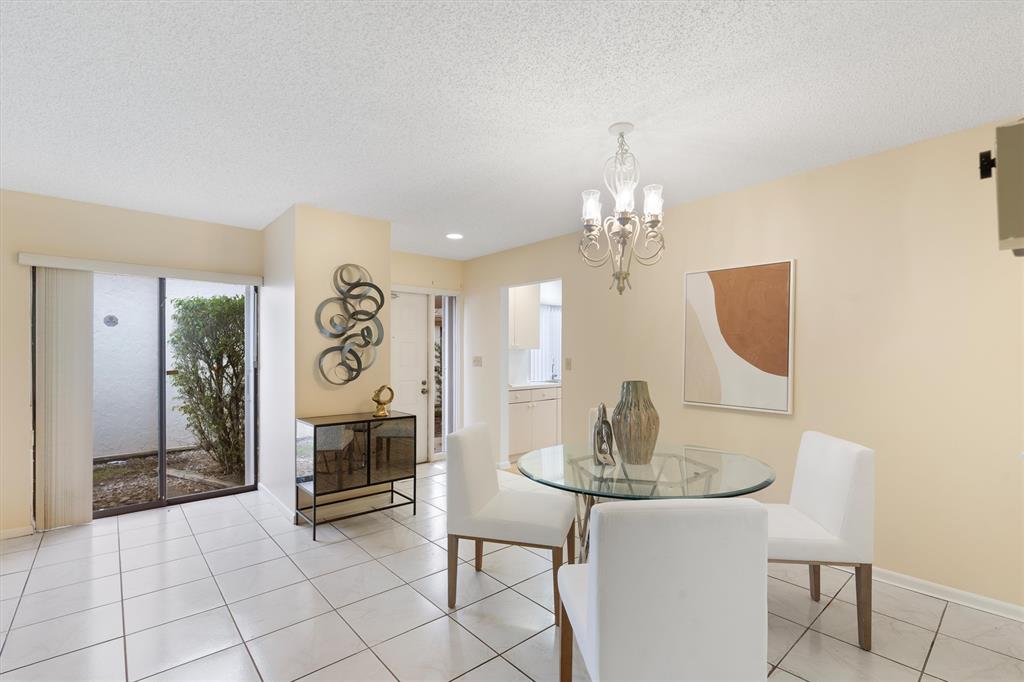 4342 Acacia Circle Coconut Creek, FL 33066 - Photo 13 of 20 a dining room with chandelier and outdoor view