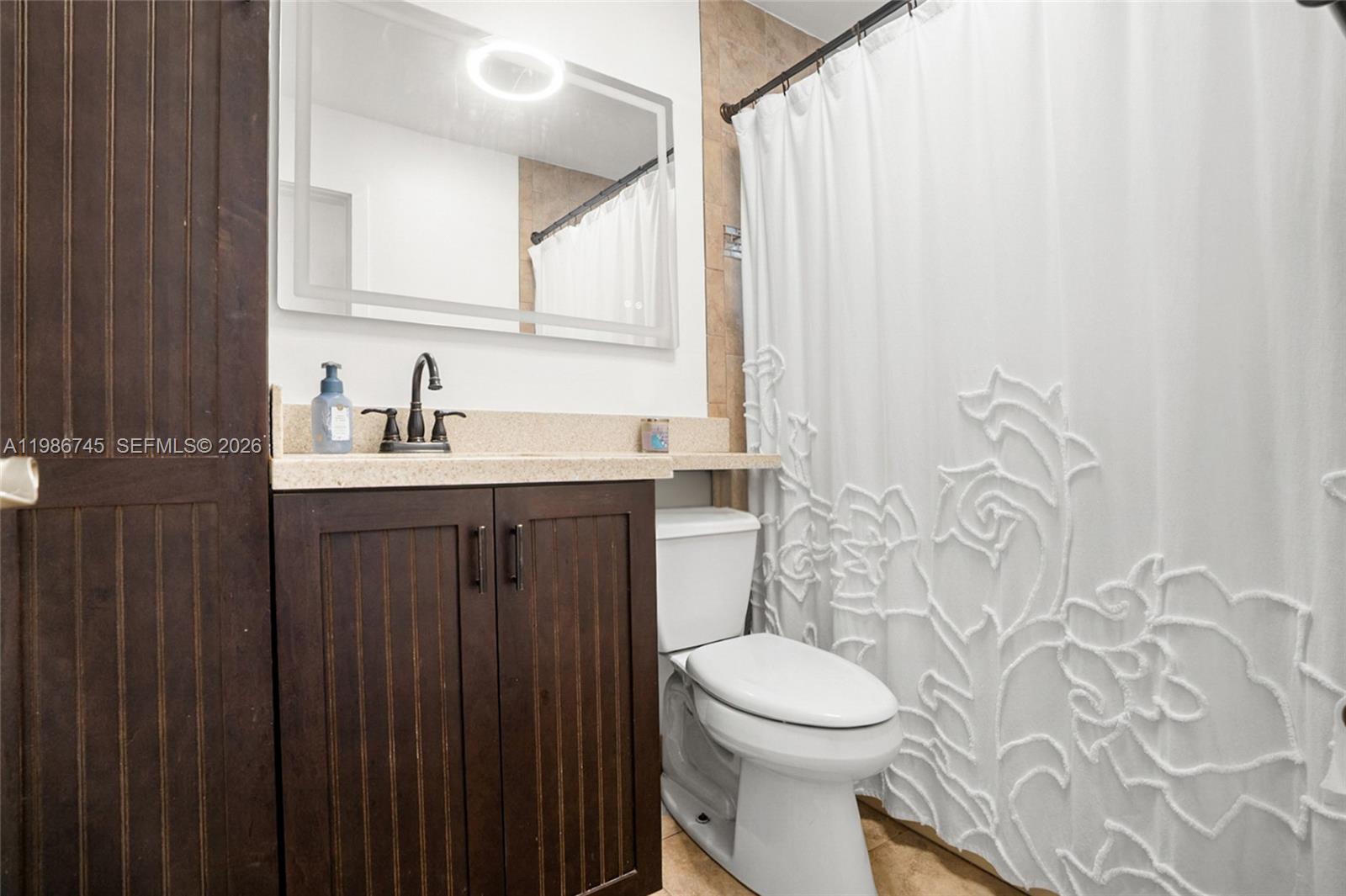2810 Northeast 11th Terrace Pompano Beach, FL 33064 - Photo 16 of 33 a bathroom with a sink a toilet and a mirror