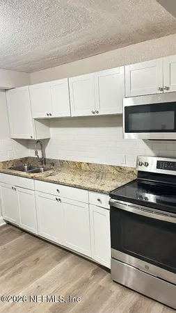 a kitchen with granite countertop a stove sink and cabinets