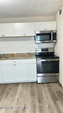 a view of kitchen with stove top oven and cabinets