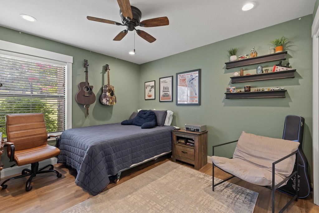 23644 Nameless Road Leander, TX 78641 - Photo 13 of 40 This cozy bedroom features a stylish ceiling fan, warm hardwood floors, and abundant natural light filtering through the window.